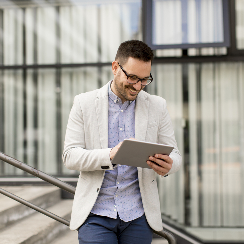 Young businessman with digital tablet by the office building